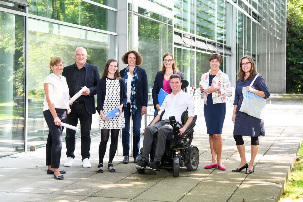 8 Beratern und Beraterinnen stehen vor der Architektenkammer, einer von ihnen sitzt im Rollstuhl.