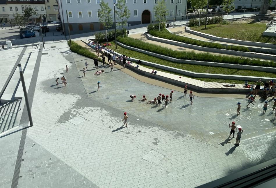 Kinder spielen in Wasser auf Marktplatz