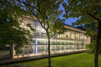 Eine Abendaufnahme des Neubaus der Bayerischen Architektenkammer. Drinnen sind Lichter an.